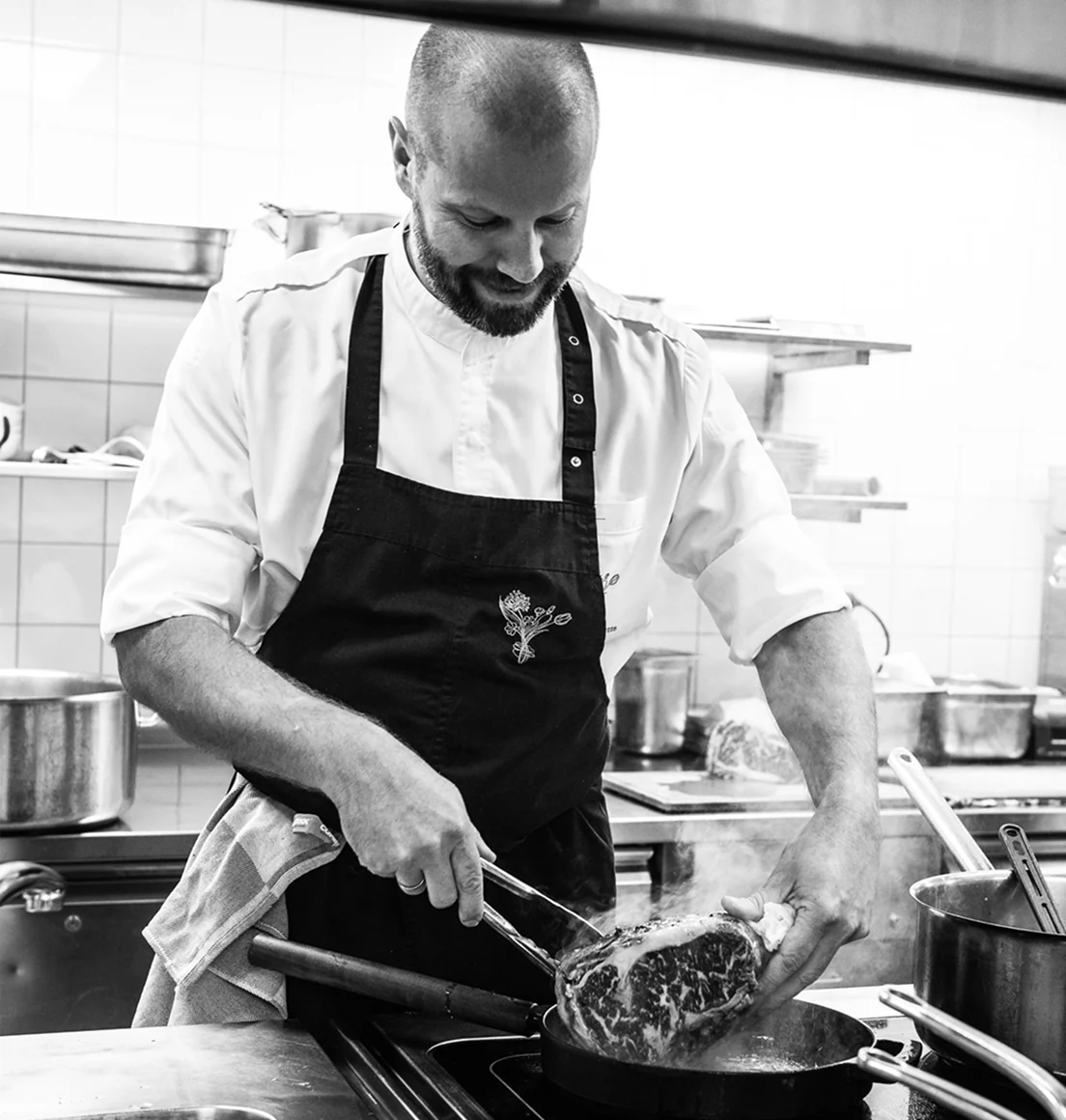 Een chef-kok bakt een groot stuk vlees in een COMBEKK-pan in een professionele keuken.